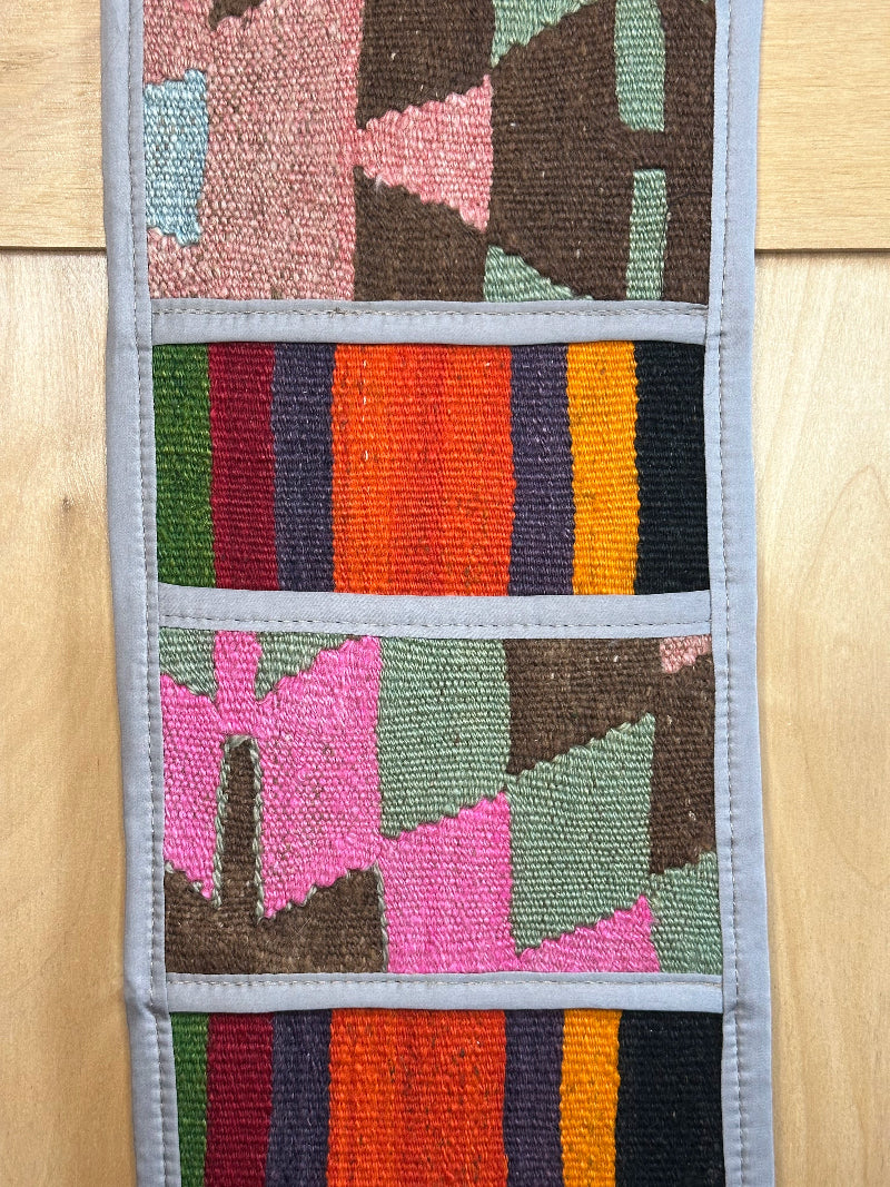 Decorative, handmade Turkish rug wall organizer with vibrant stripe designs and 3 storage pockets. Upcycled vintage textile art by High Pile Designs.