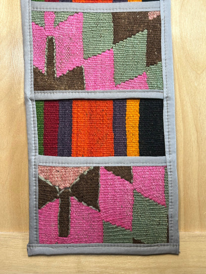 Decorative, handmade Turkish rug wall organizer with vibrant stripe designs and 3 storage pockets. Upcycled vintage textile art by High Pile Designs.