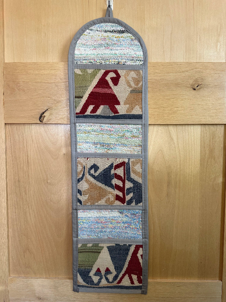 Decorative, handmade Turkish rug wall organizer with vibrant stripe designs and 3 storage pockets. Upcycled vintage textile art by High Pile Designs. Featuring wrapped gifts.