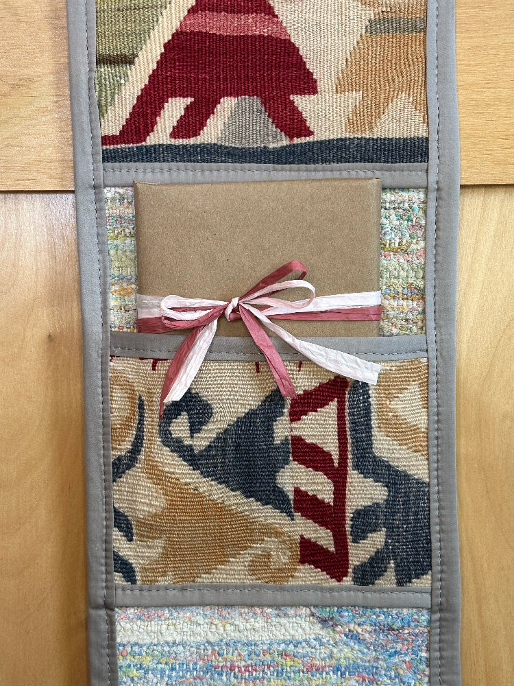 Decorative, handmade Turkish rug wall organizer with vibrant stripe designs and 3 storage pockets. Upcycled vintage textile art by High Pile Designs. Featuring wrapped gifts.