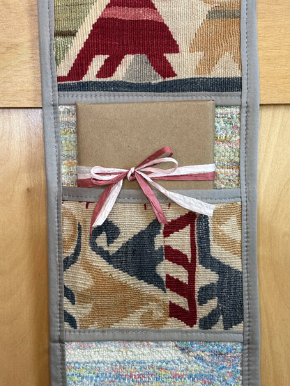 Decorative, handmade Turkish rug wall organizer with vibrant stripe designs and 3 storage pockets. Upcycled vintage textile art by High Pile Designs. Featuring wrapped gifts.