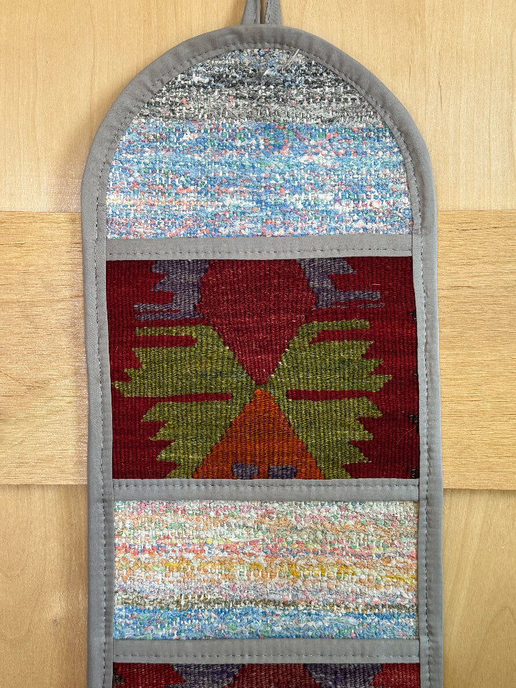 Decorative, handmade Turkish rug wall organizer with vibrant stripe designs and 3 storage pockets. Upcycled vintage textile art by High Pile Designs. Featuring wrapped gifts.