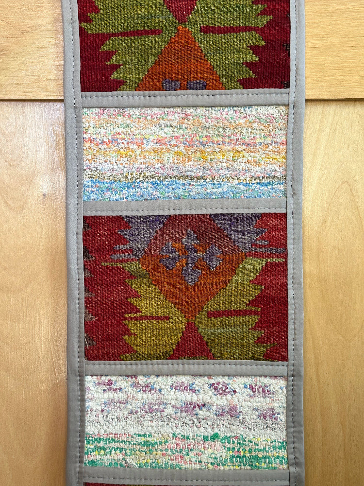 Decorative, handmade Turkish rug wall organizer with vibrant stripe designs and 3 storage pockets. Upcycled vintage textile art by High Pile Designs. Featuring wrapped gifts.