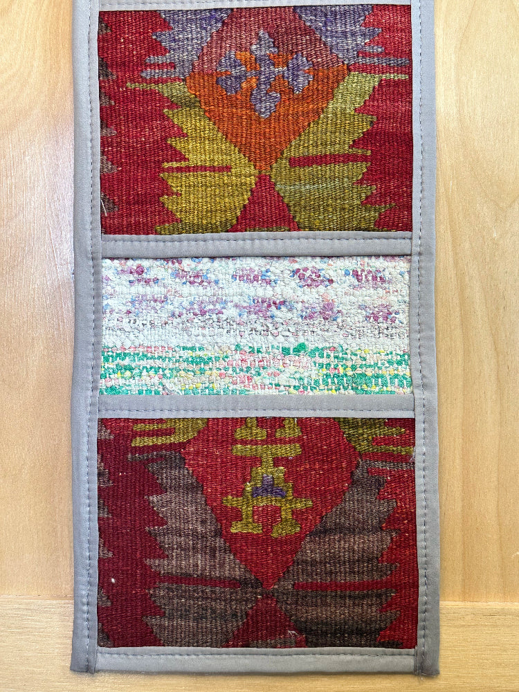 Decorative, handmade Turkish rug wall organizer with vibrant stripe designs and 3 storage pockets. Upcycled vintage textile art by High Pile Designs. Featuring wrapped gifts.