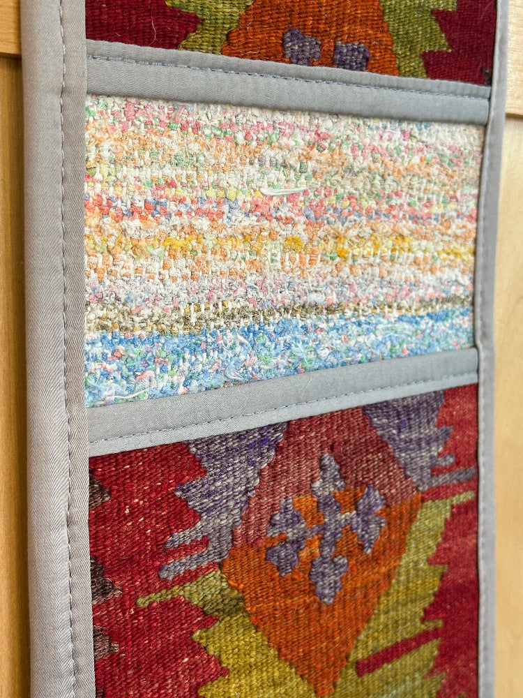 Decorative, handmade Turkish rug wall organizer with vibrant stripe designs and 3 storage pockets. Upcycled vintage textile art by High Pile Designs. Featuring wrapped gifts.
