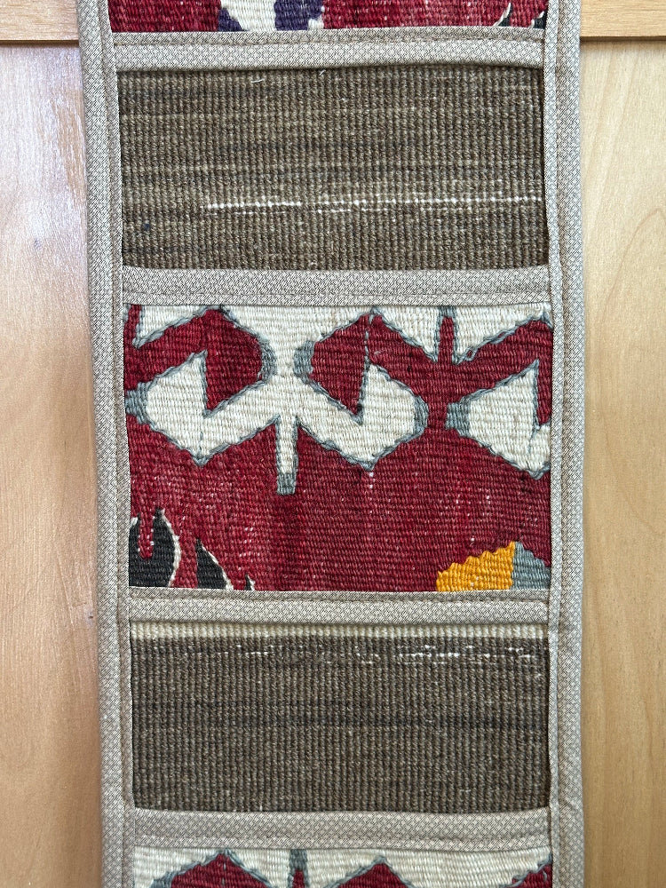 Decorative, handmade Turkish rug wall organizer with vibrant stripe designs and 3 storage pockets. Upcycled vintage textile art by High Pile Designs. 