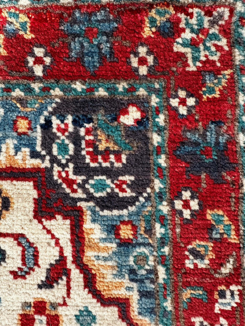 Handknotted two by three foot mini Kazak rug with intricate geometric patterns, rich red and deep blue hues, and a durable low-pile wool construction. Made to order in custom sizes, perfect for adding a bold, traditional touch to vintage, classic, or eclectic home décor.