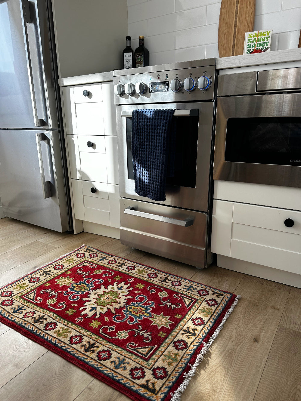 Hand-knotted 2x3 foot mini pile rug featuring a colorful geometric design, large central motif and geometric border - wool material with pops of red, green, navy and white. 