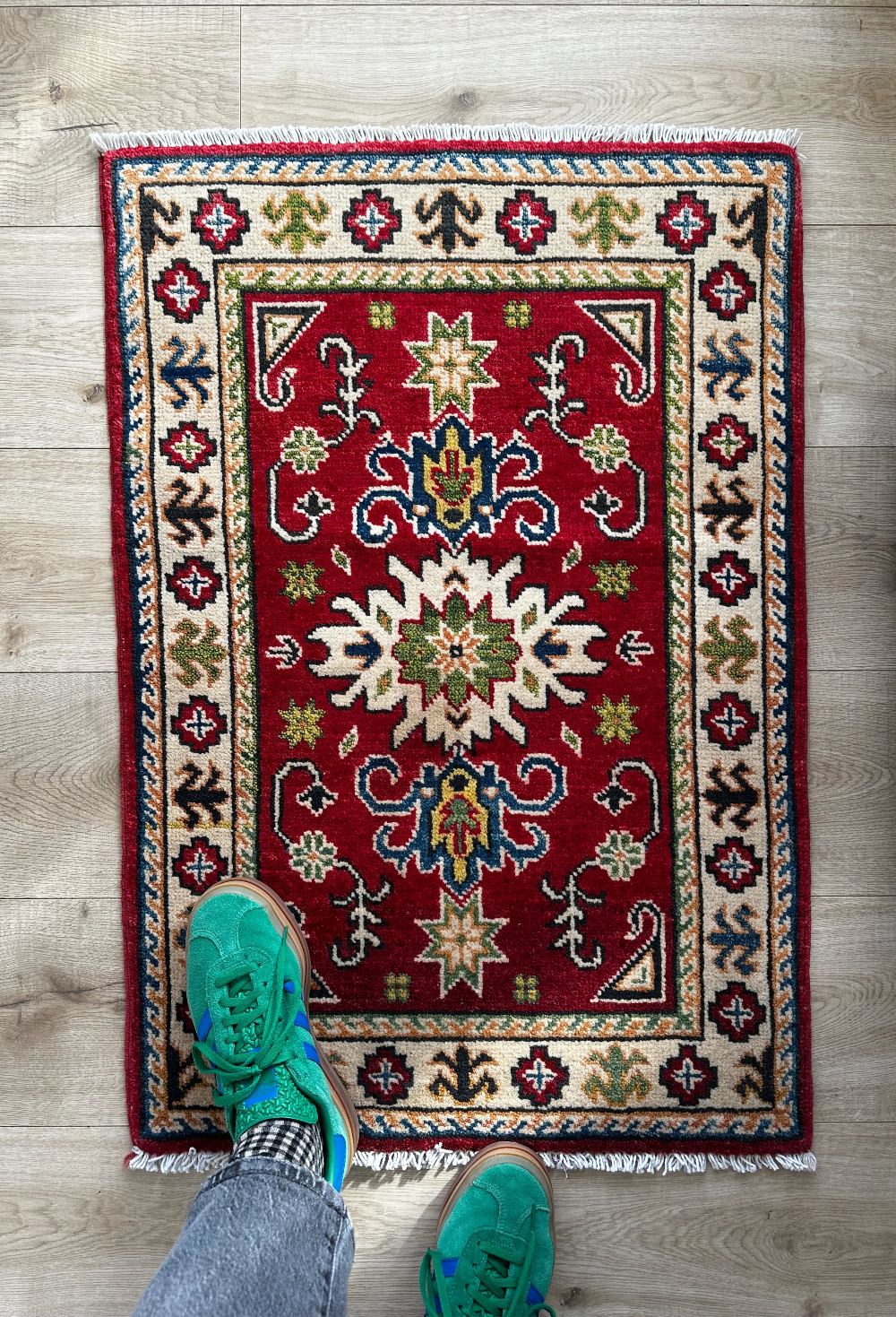 Hand-knotted 2x3 foot mini pile rug featuring a colorful geometric design, large central motif and geometric border - wool material with pops of red, green, navy and white. 