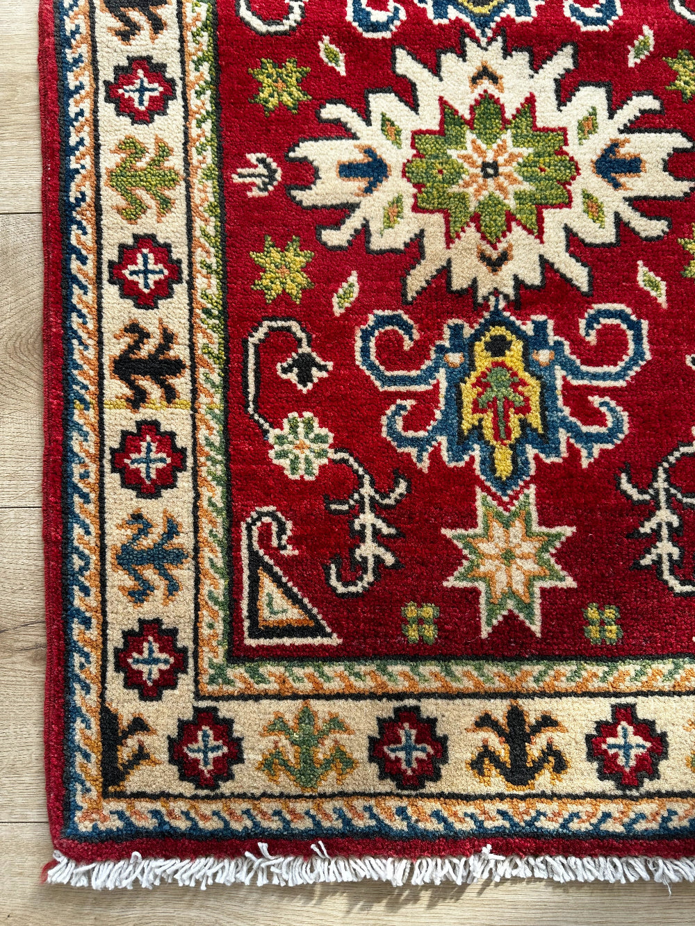 Hand-knotted 2x3 foot mini pile rug featuring a colorful geometric design, large central motif and geometric border - wool material with pops of red, green, navy and white. 