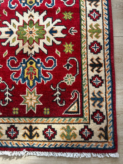 Hand-knotted 2x3 foot mini pile rug featuring a colorful geometric design, large central motif and geometric border - wool material with pops of red, green, navy and white. 