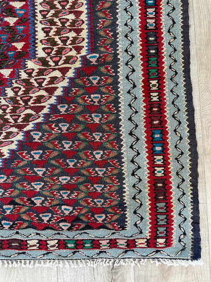 Handwoven Senneh Kilim rug, featuring intricate geometric patterns, a central medallion design, and rich earthy red, deep blue, and neutral tones. Flat-woven wool rug with fine detailing and a slit tapestry weave, perfect for bohemian, modern, or traditional home décor.