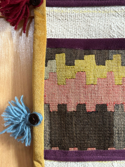 Handmade Turkish wall hanging with vintage rug patterns, featuring colorful tassels, evil eye beads, and geometric designs on a wood panel background. Unique bohemian decor made from authentic Turkish rug fragments, perfect for home styling.