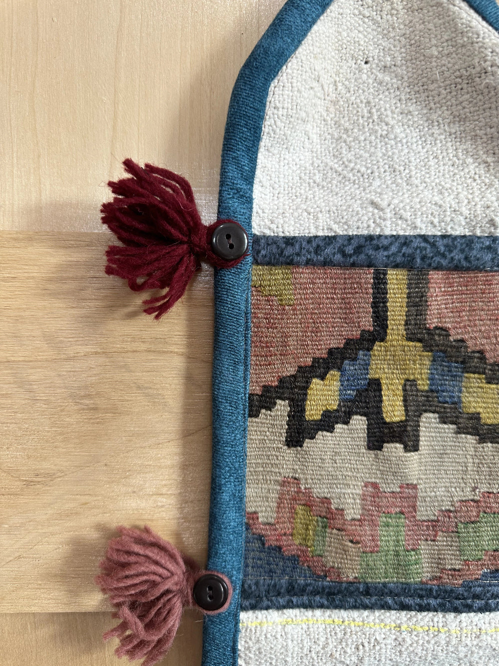 Handmade Turkish wall hanging with vintage rug patterns, featuring colorful tassels, evil eye beads, and geometric designs on a wood panel background. Unique bohemian decor made from authentic Turkish rug fragments, perfect for home styling.