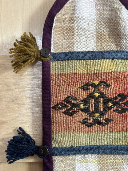 Handmade Turkish wall hanging with vintage rug patterns, featuring colorful tassels, evil eye beads, and geometric designs on a wood panel background. Unique bohemian decor made from authentic Turkish rug fragments, perfect for home styling.