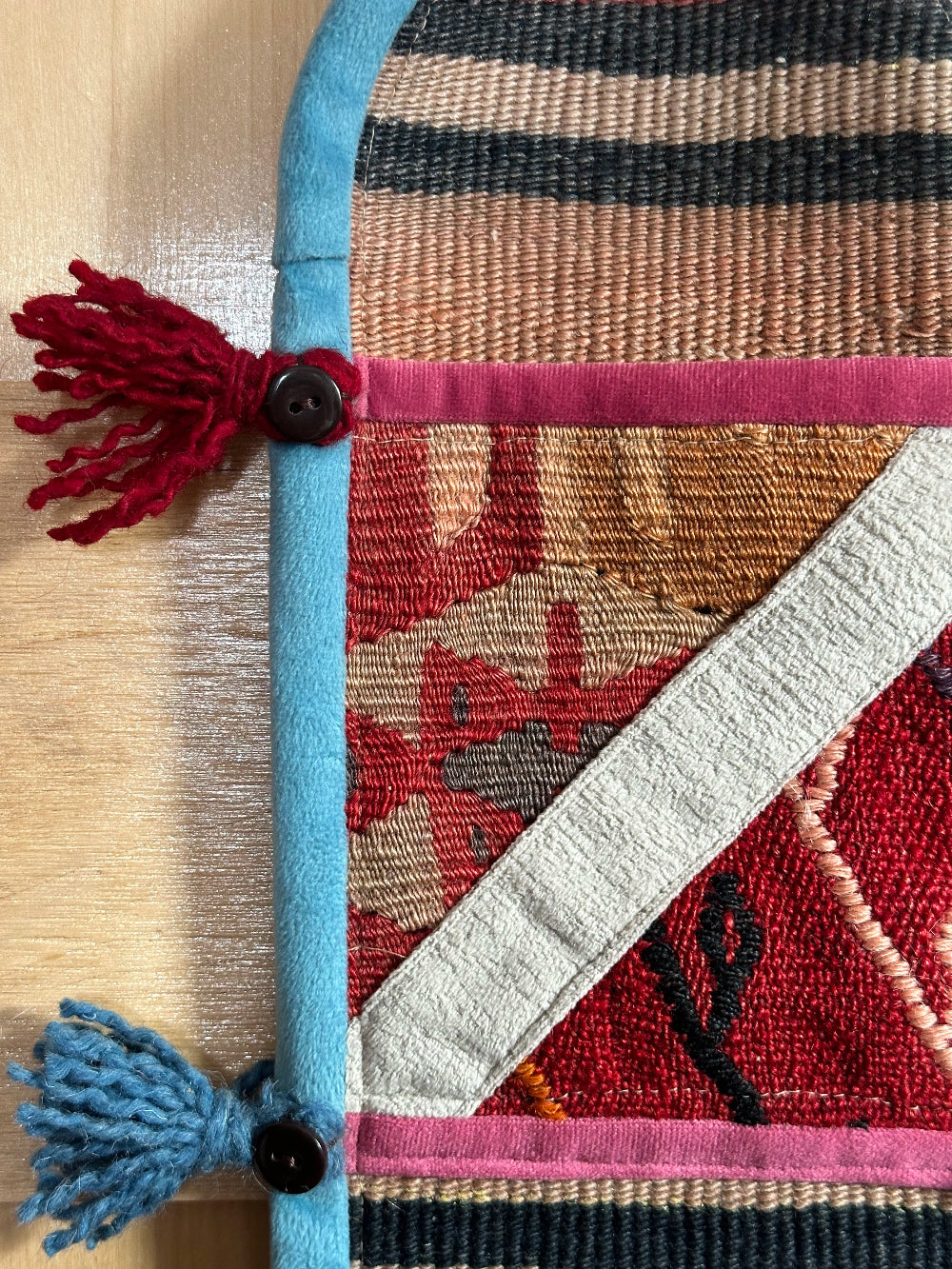 Handmade Turkish wall hanging with vintage rug patterns, featuring colorful tassels, evil eye beads, and geometric designs on a wood panel background. Unique bohemian decor made from authentic Turkish rug fragments, perfect for home styling.