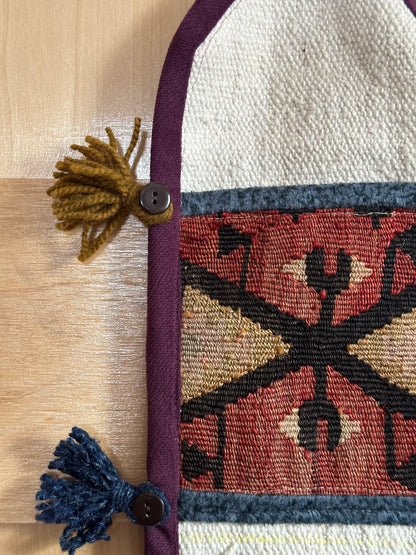 Handmade Turkish wall hanging with vintage rug patterns, featuring colorful tassels, evil eye beads, and geometric designs on a wood panel background. Unique bohemian decor made from authentic Turkish rug fragments, perfect for home styling.