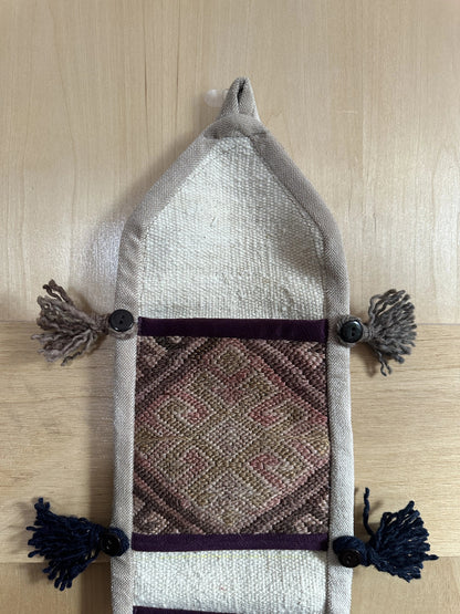 Handmade Turkish wall hanging with vintage rug patterns, featuring colorful tassels, evil eye beads, and geometric designs on a wood panel background. Unique bohemian decor made from authentic Turkish rug fragments, perfect for home styling.