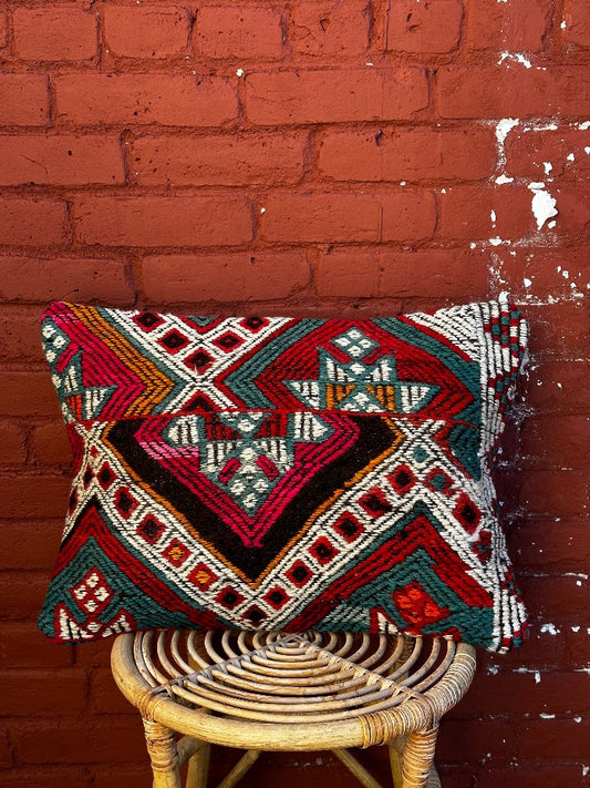 16 by 24 colorful Turkish lumbar pillow featuring multicolor shapes and lines with pops of red and green
