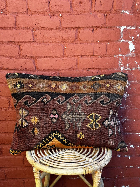 16 by 24 Turkish lumbar pillow featuring a muted color palette of browns and purples and accent colors of orange and yellow with geometric patterns throughout upcycled from a Turkish rug