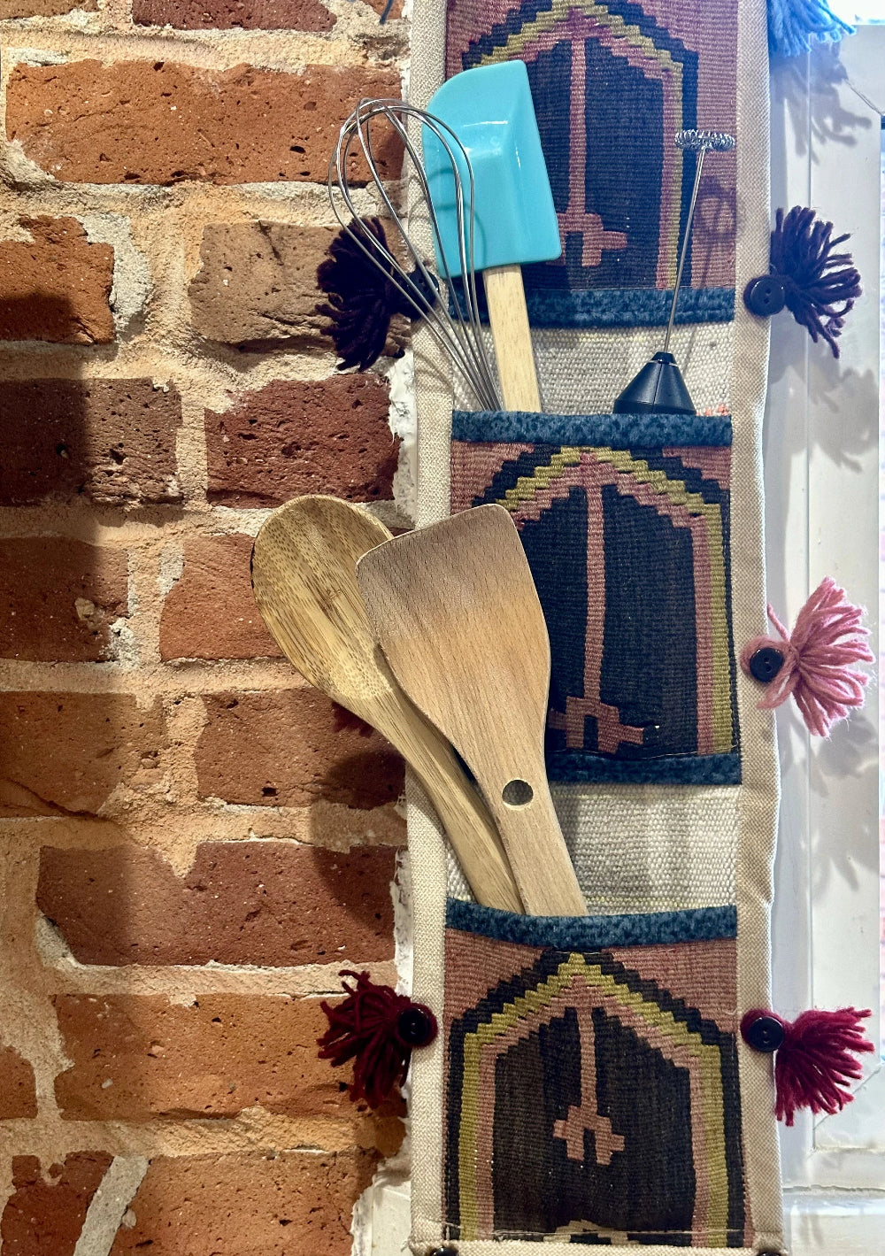 Handmade Turkish wall hanging with vintage rug patterns, featuring colorful tassels, evil eye beads, and geometric designs on a wood panel background. Unique bohemian decor made from authentic Turkish rug fragments, perfect for home styling.