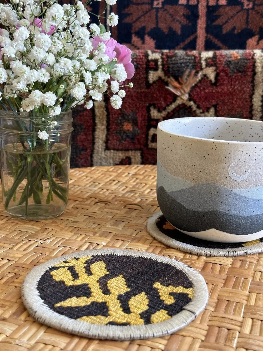 Set of 2 Turkish fabric coasters made from recycled rug and pillow fabric, featuring yellow and orange floral pattern on black background