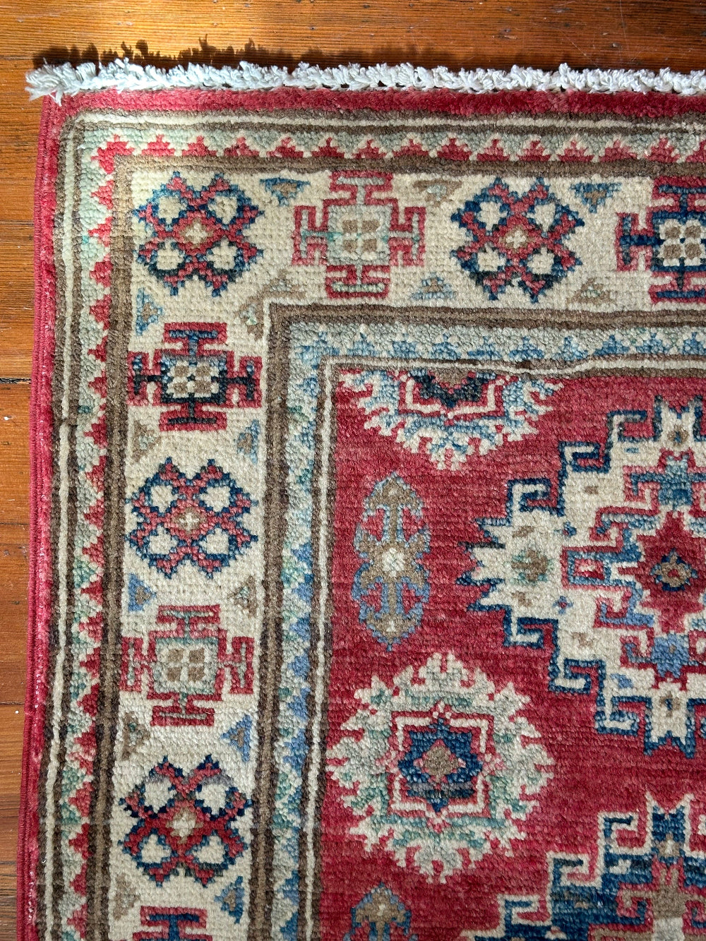 Hand-knotted 2x3 foot mini pile rug featuring a colorful geometric design, large central motif and geometric border - wool material with pops of red, light blue, navy and white. 