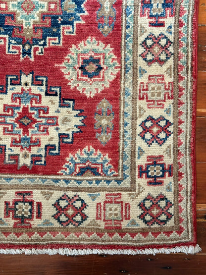 Hand-knotted 2x3 foot mini pile rug featuring a colorful geometric design, large central motif and geometric border - wool material with pops of red, light blue, navy and white. 