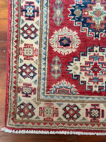 Hand-knotted 2x3 foot mini pile rug featuring a colorful geometric design, large central motif and geometric border - wool material with pops of red, light blue, navy and white. 