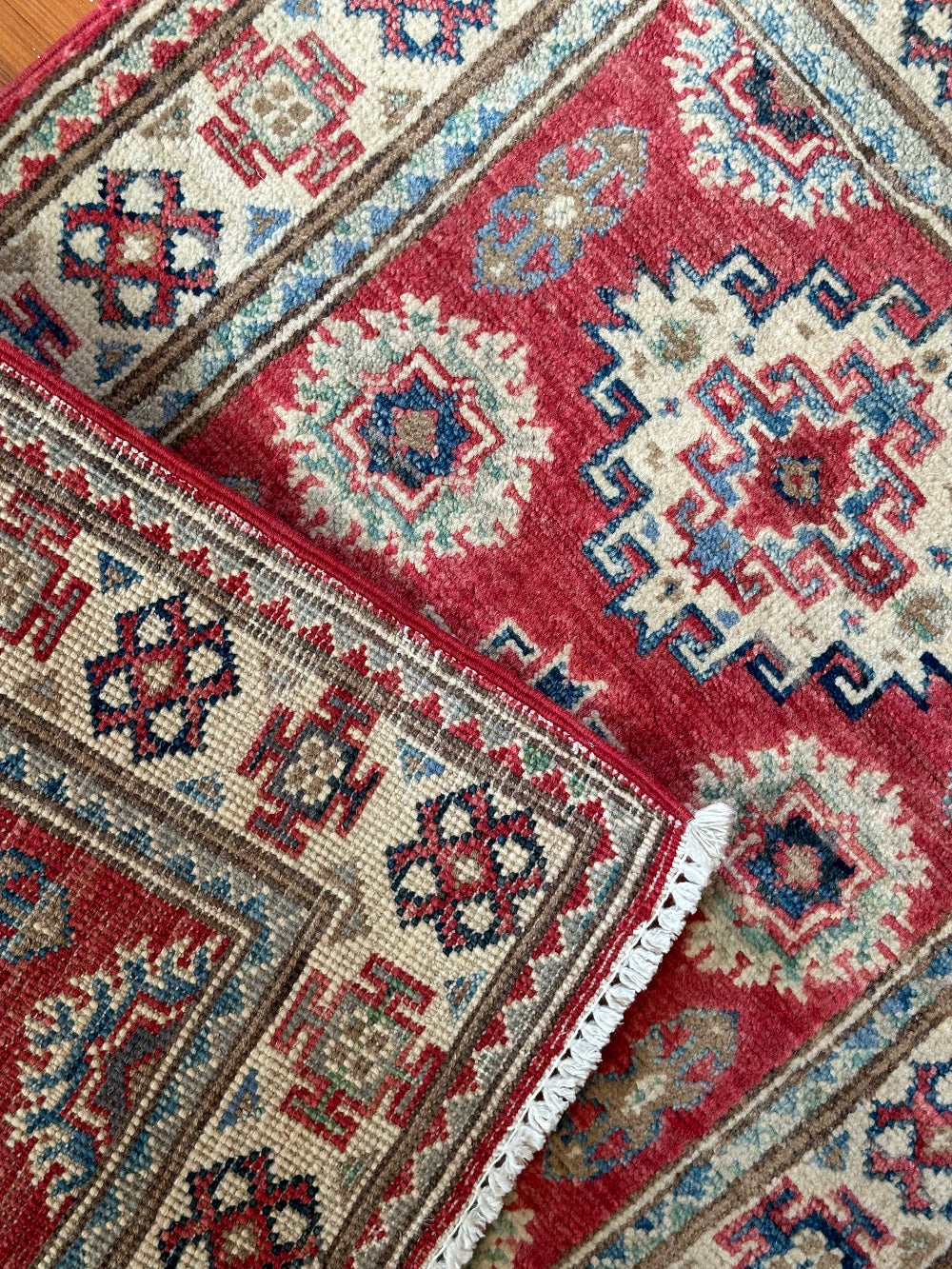 Hand-knotted 2x3 foot mini pile rug featuring a colorful geometric design, large central motif and geometric border - wool material with pops of red, light blue, navy and white. 