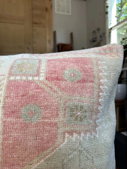16 by 24 neutral Turkish Lumbar pillow featuring pops of pink and geometric floral pattern throughout