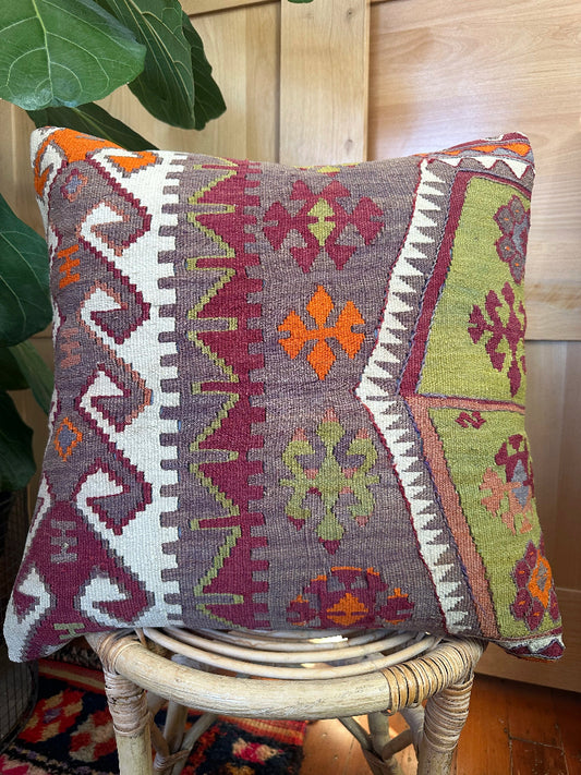 Eco-conscious kilim pillow handcrafted from repurposed Turkish rugs. Features rich geometric patterns in olive, rust, plum, and ivory tones.