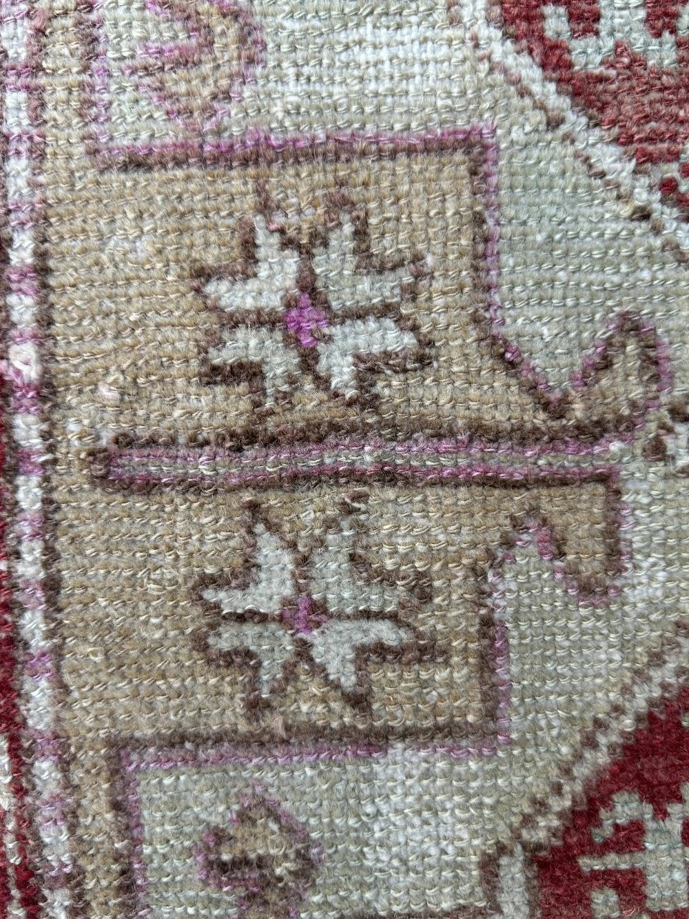 4 by 2 small Turkish area rug featuring deep red hues and light sand and tan coloring with two large medallions in the center bordered by geometric shapes and florals