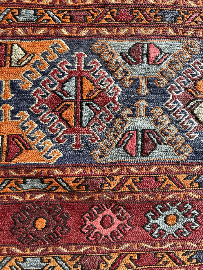 5 by 3 red and orange Turkish area rug featuring a striped pattern on the outside edges and a central striped pattern with geometric shapes and embroidery