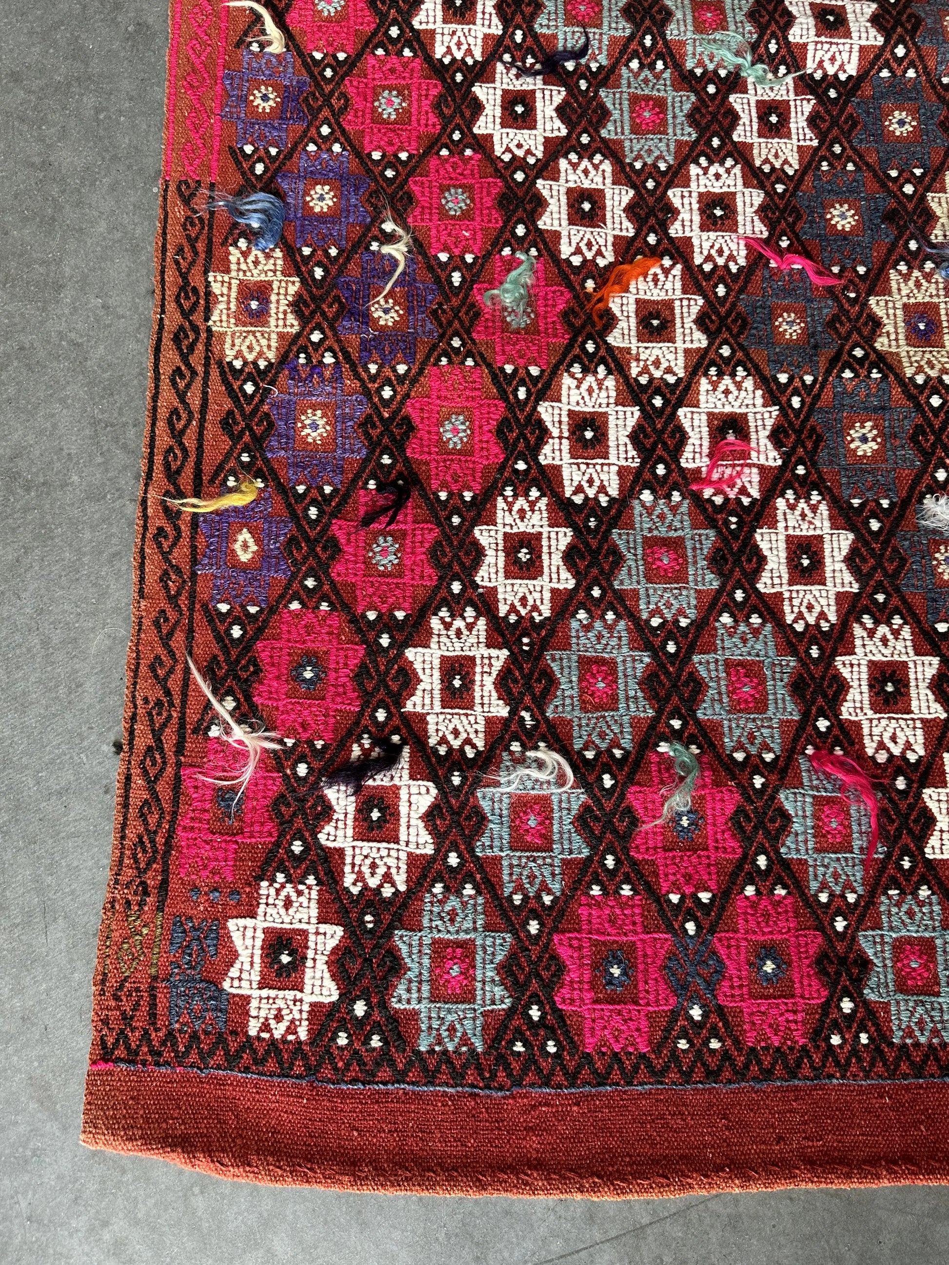 5.5 by 3.8 ft red Turkish area rug and tapestry with fringe, featuring white, pink, purple and blue 8-pointed stars