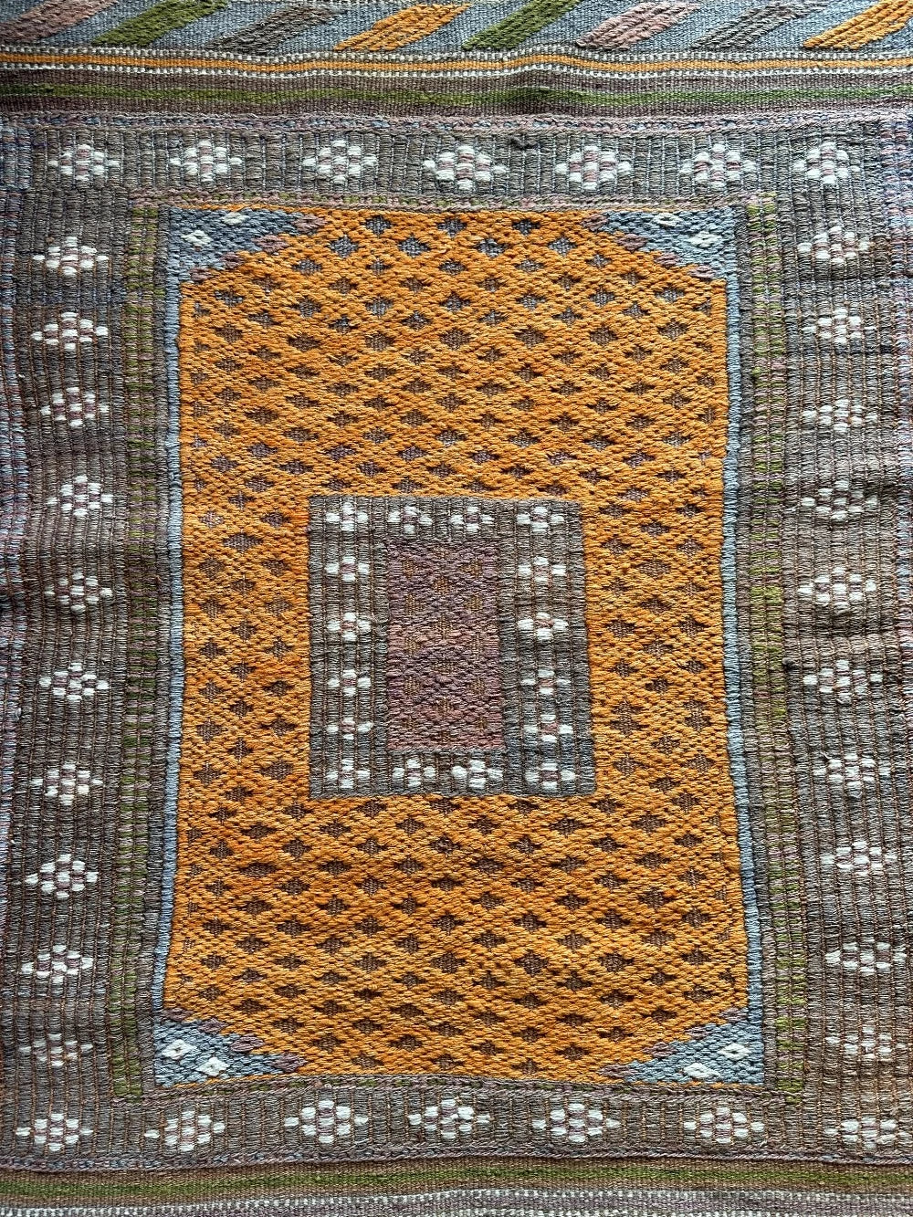 4.5 by 3 colorful turkish area rug featuring bright pops of orange and muted neutrals and pops of blue and green