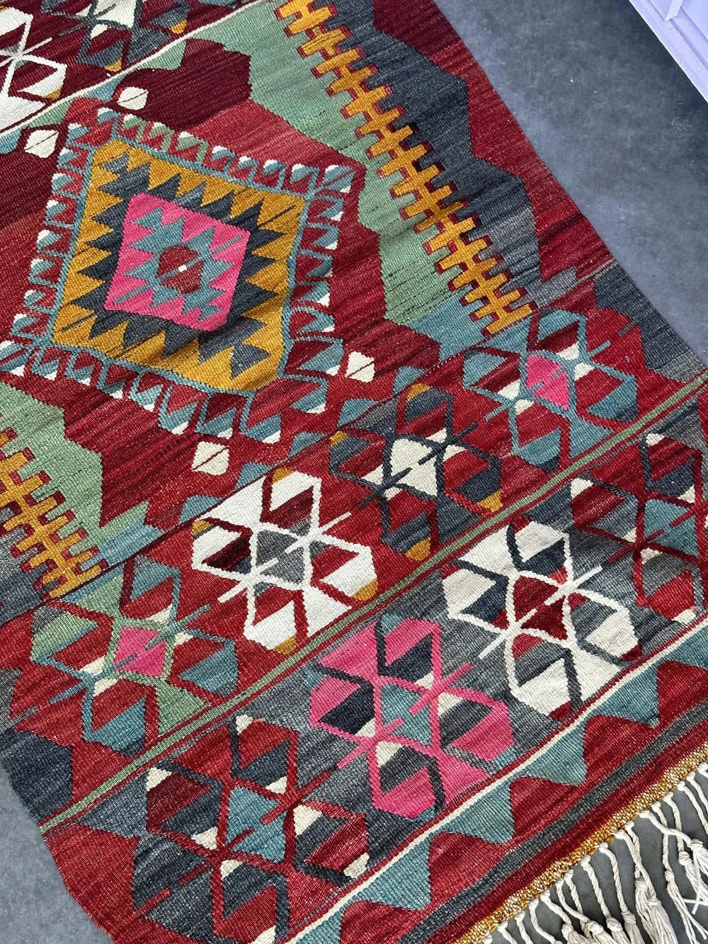 5.5 by 2.9 foot colorful Turkish area rug featuring diamond geometric patterns and bright accent colors