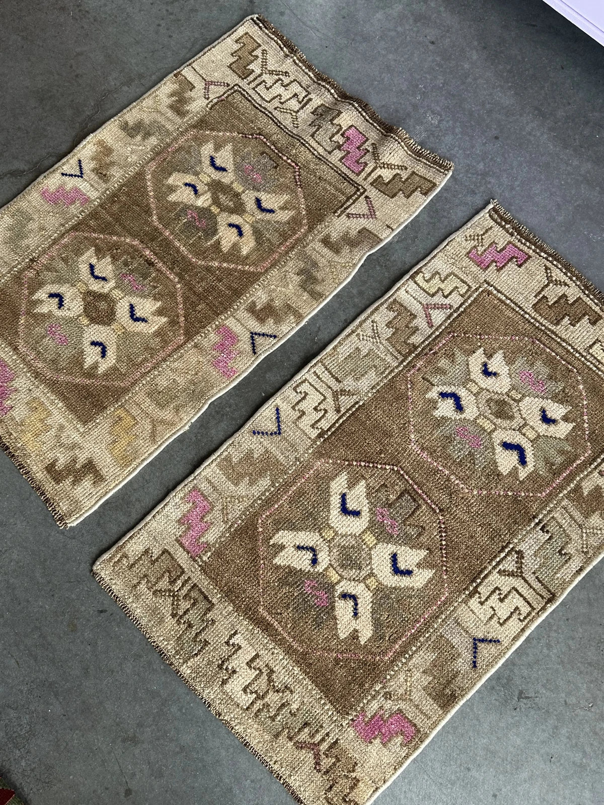 Handmade neutral Turkish mini rug featuring sand, brown and pops of pink and blue with geometric patterns around the border