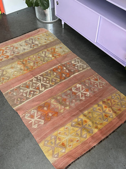 small Turkish flatwoven kilim rug featuring sunset coloring, sherbet pink and sunshine yellow and geometric striped pattern throughout