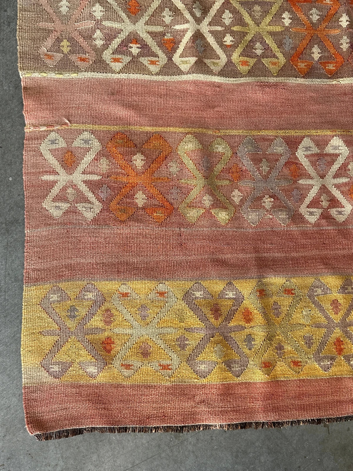 small Turkish flatwoven kilim rug featuring sunset coloring, sherbet pink and sunshine yellow and geometric striped pattern throughout