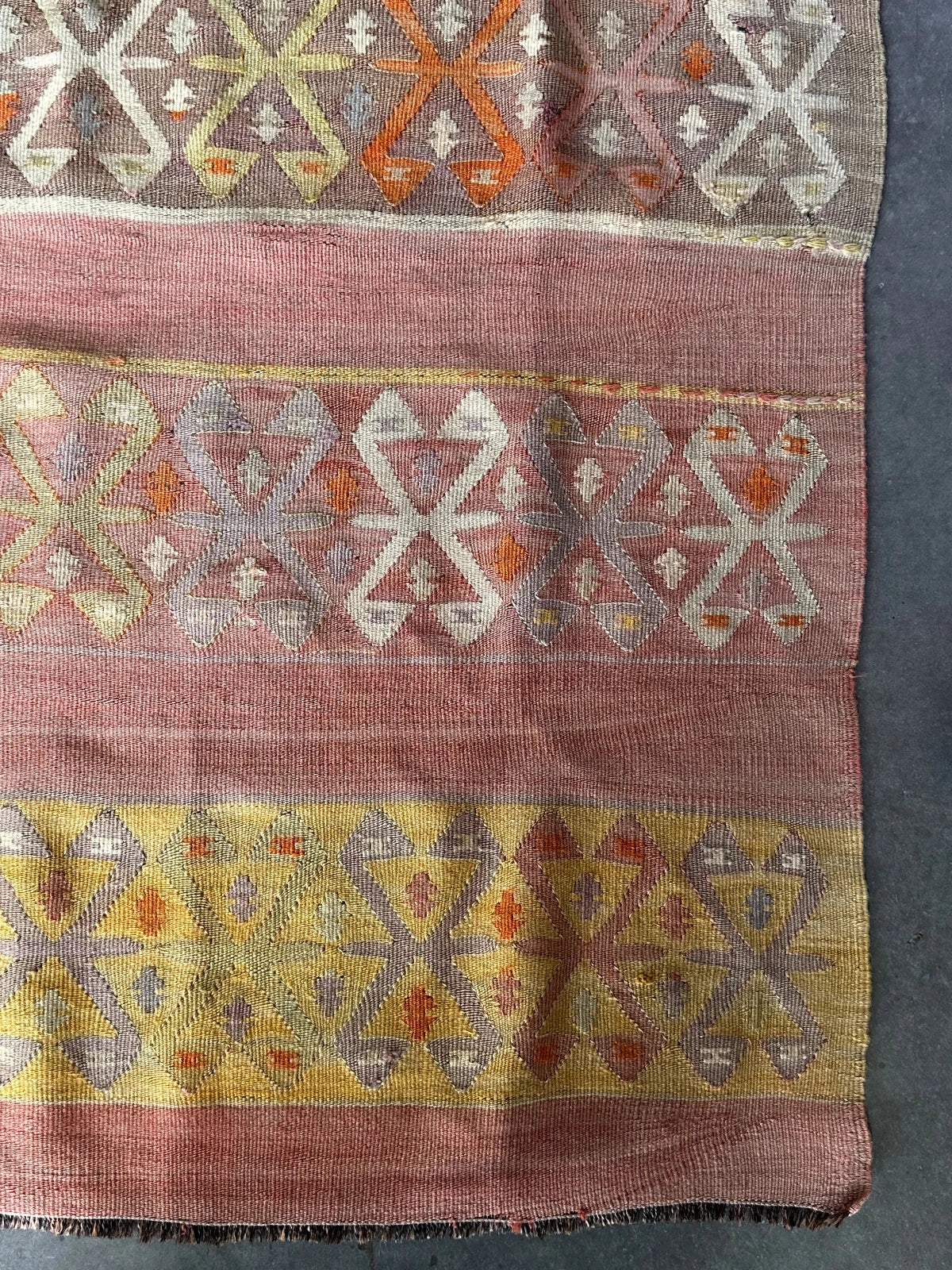 small Turkish flatwoven kilim rug featuring sunset coloring, sherbet pink and sunshine yellow and geometric striped pattern throughout