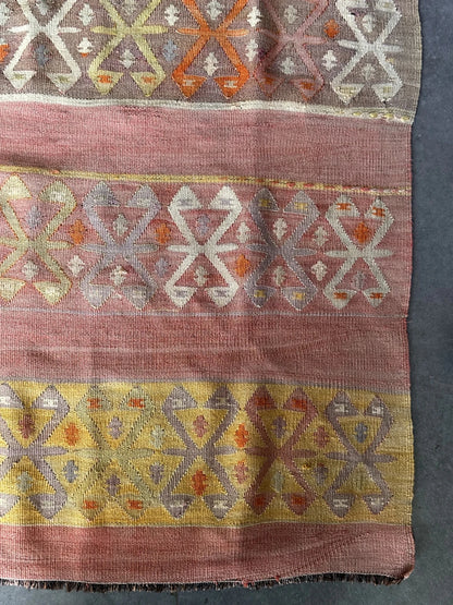 small Turkish flatwoven kilim rug featuring sunset coloring, sherbet pink and sunshine yellow and geometric striped pattern throughout