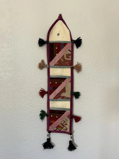 multi-colored three pocket wall organizer made from scraps of colorful Turkish kilim rugs with yarn tassels at each end