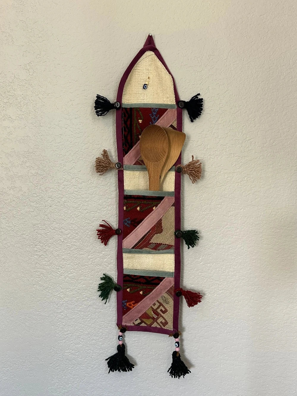 multi-colored three pocket wall organizer made from scraps of colorful Turkish kilim rugs with yarn tassels at each end