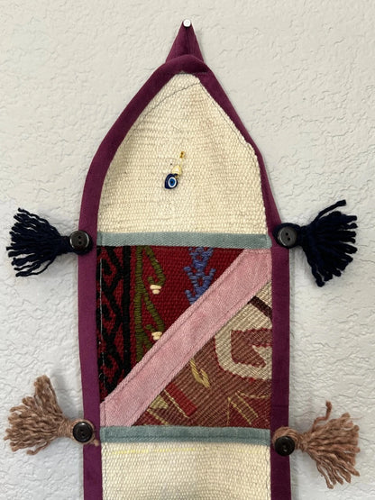 multi-colored three pocket wall organizer made from scraps of colorful Turkish kilim rugs with yarn tassels at each end