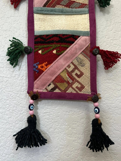 multi-colored three pocket wall organizer made from scraps of colorful Turkish kilim rugs with yarn tassels at each end