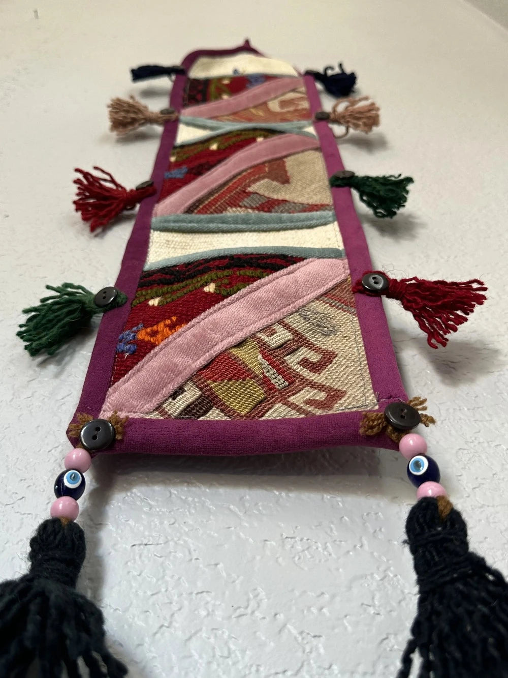 multi-colored three pocket wall organizer made from scraps of colorful Turkish kilim rugs with yarn tassels at each end