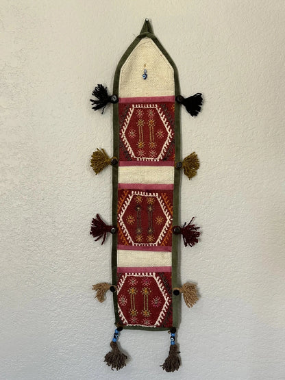 multi-colored three pocket wall organizer made from scraps of colorful Turkish kilim rugs with yarn tassels at each end