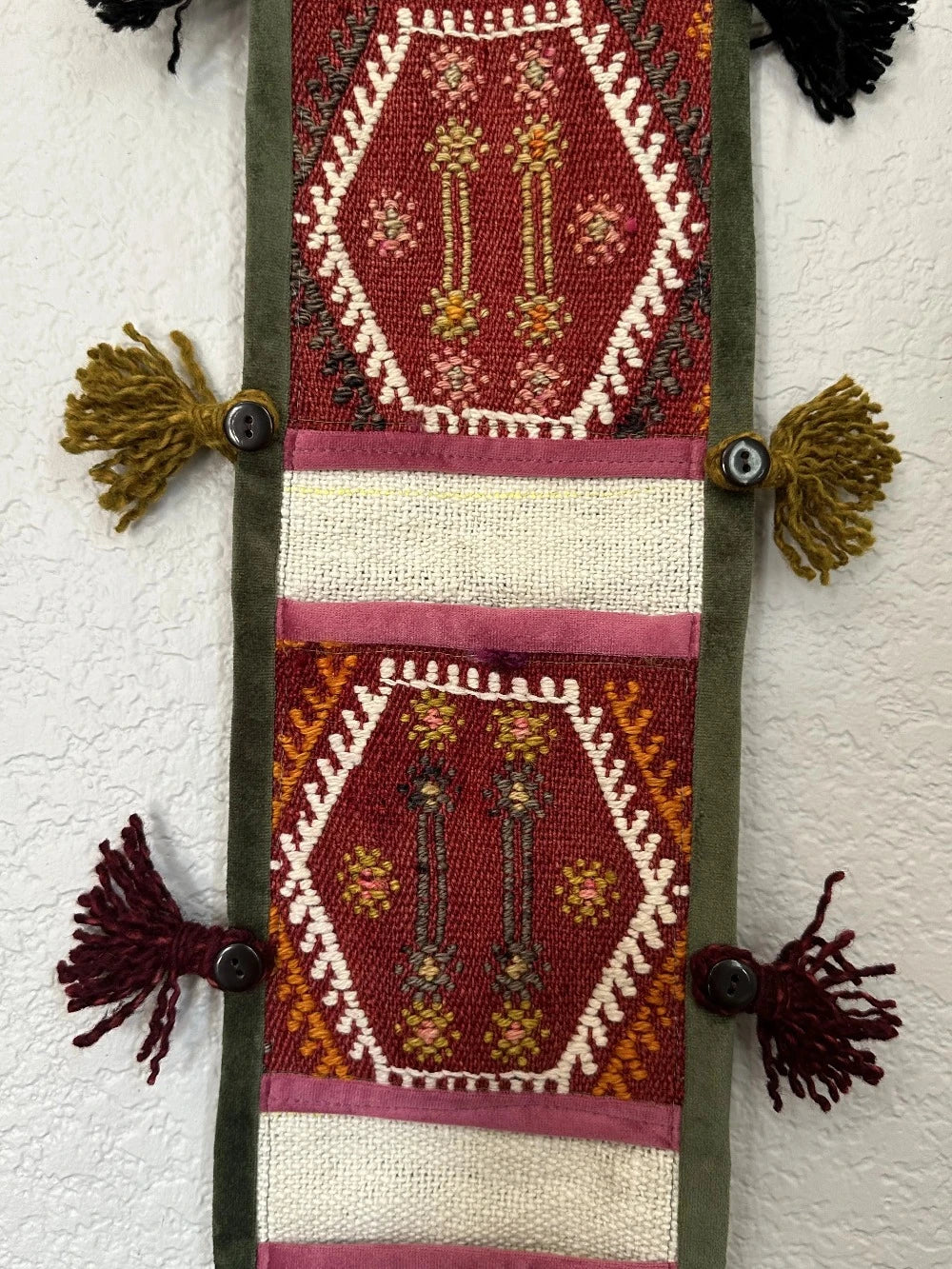 multi-colored three pocket wall organizer made from scraps of colorful Turkish kilim rugs with yarn tassels at each end