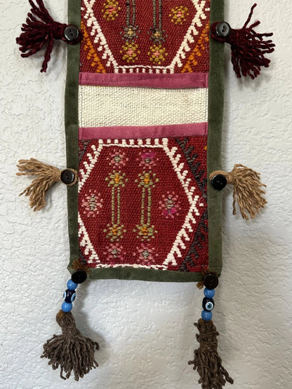 multi-colored three pocket wall organizer made from scraps of colorful Turkish kilim rugs with yarn tassels at each end